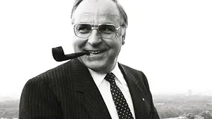 Porträtfoto von Helmut Kohl, lachend, mit einer Tabakpfeife im Mund.