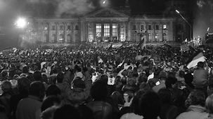 Eine große Menschenmenge feiert in der Nacht vom 2. zum 3. Oktober 1990 die Wiedervereinigung Deutschlands mit einem Feuerwerk vor dem Reichstagsgebäude in Berlin. 