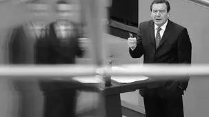 Gerhard Schröder steht am Rednerpult im Reichstag und hält eine Rede.