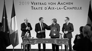 Bundeskanzlerin Merkel, Frankreichs Präsident Macron und die Außenminister beider Länder, Maaß und Le Drian, bei der Unterzeichnung des Abkommens. 