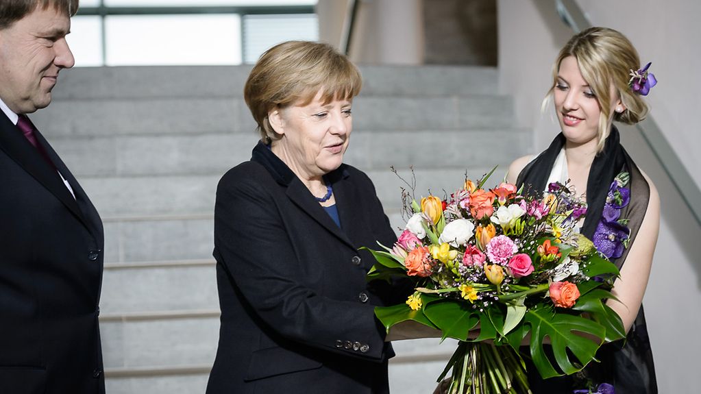 Bundeskanzlerin Angela Merkel bekommt Blumen.