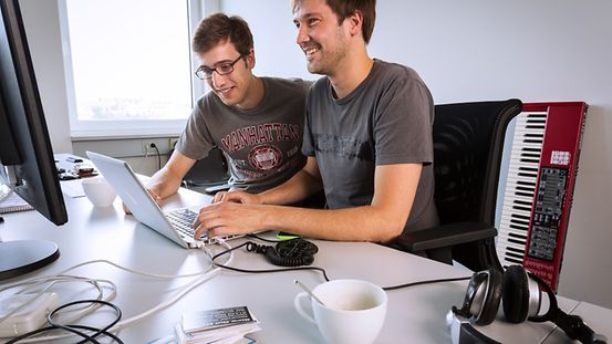 Zwei Geschäftsführer eines Berliner Startup-Unternehmens vor dem Laptop.