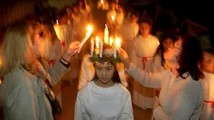 Ein Mädchen – traditionell die älteste Tochter einer Familie – trägt einen Kranz aus Kerzen auf dem Kopf und stellt die heilige Lucia dar, die symbolisch Licht und Wärme in die dunkelste und kälteste Zeit des Jahres bringt.