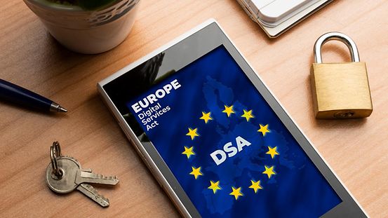 Auf eine Handy-Display ist eine europäische Flagge und der Schriftzug "Europe Digital Services Act DSA" zu lesen.