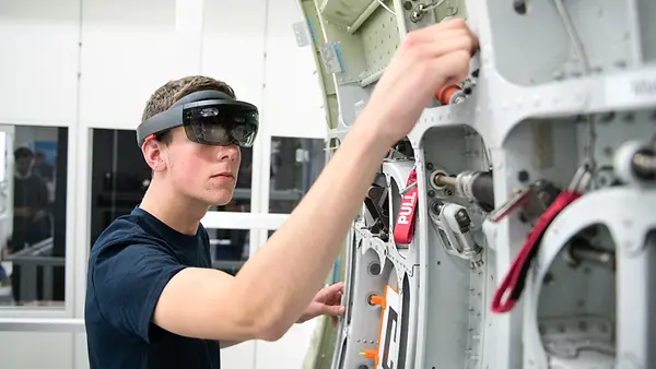 Ein Airbus-Auszubildender zeigt bei einer Demonstration den Einsatz einer Datenbrille (Microsoft Hololens) an einem Flugzeugbauteil.