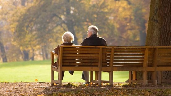 Senior citizens sitting on a park bench in autumn