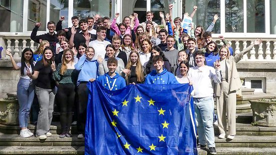 Die rund 50 Teilnehmerinnen und Teilnehmer des EU-Camps stehen auf einer Treppe und jubeln in die Kamera. Zwei