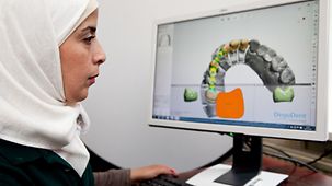 Wessal Alkhalil, Zahntechnikerin in Hamburg, sitzt vor einem Computer mit 3D-Animation eines Unterkiefers.