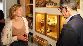 Bundeslandwirtschaftsminister Cem Özdemirs Besuch im Foodsharing-Café Raupe Immersatt in Stuttgart. Er spricht vor einer Brötchentheke mit einer Frau.