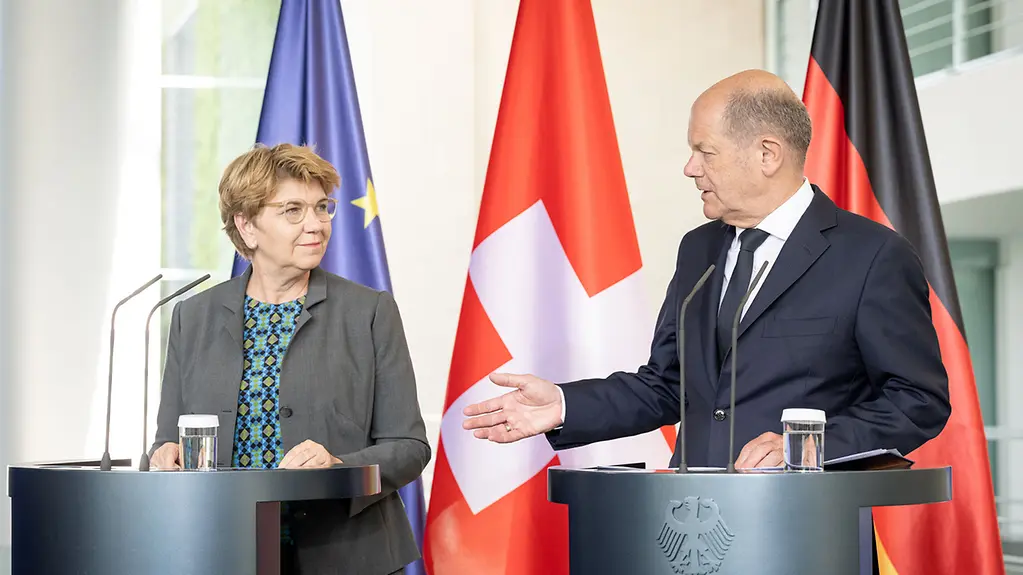 Amherd (l-) und Scholz (r.) an Rednerpulten vor den Nationalflaggen
