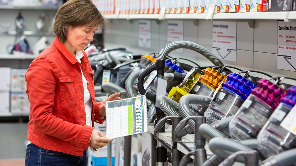 Eine Frau informiert sich in einem Elektronikmarkt über Staubsauger.