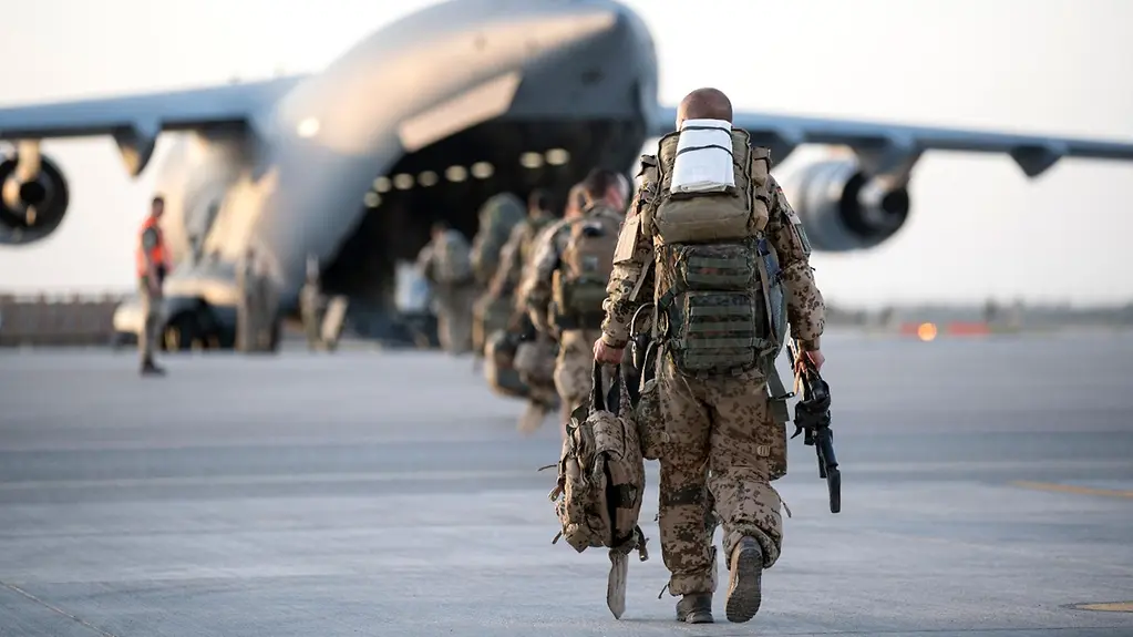 The photo shows soldiers of the Federal Armed Forces walking across an airfield.