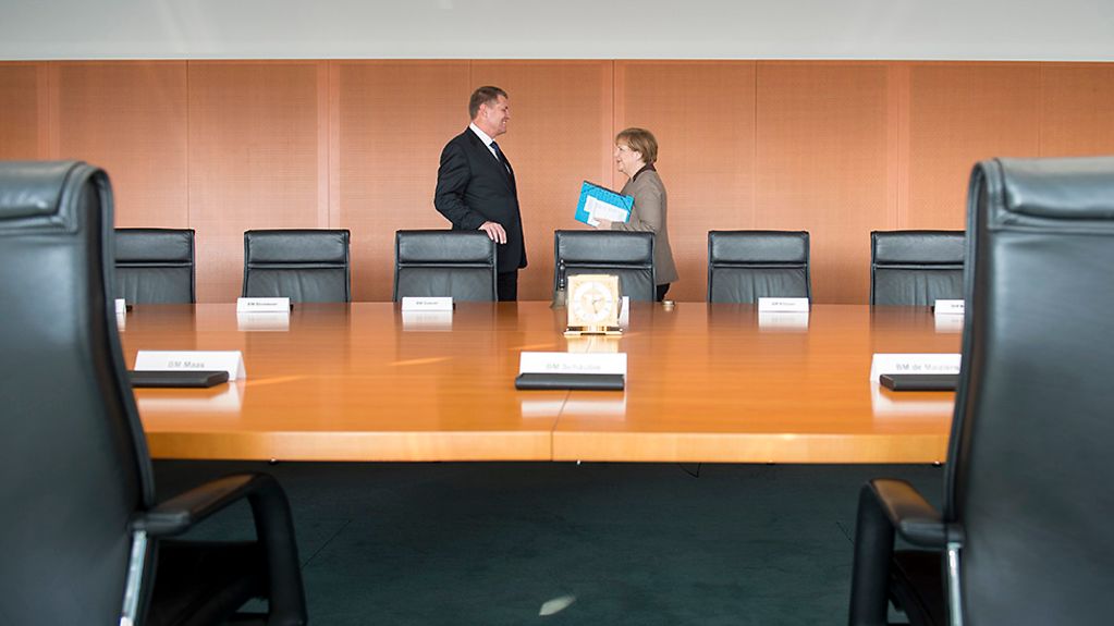 Ministerpräsident und Bundeskanzlerin im Gespräch hinter dem Kabinettstisch.