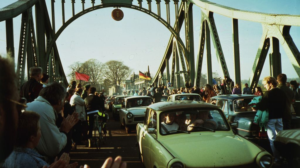 The people of West Berlin welcome visitors from Potsdam on the Glienicke Bridge. An East German Trabant can be seen in the foreground.