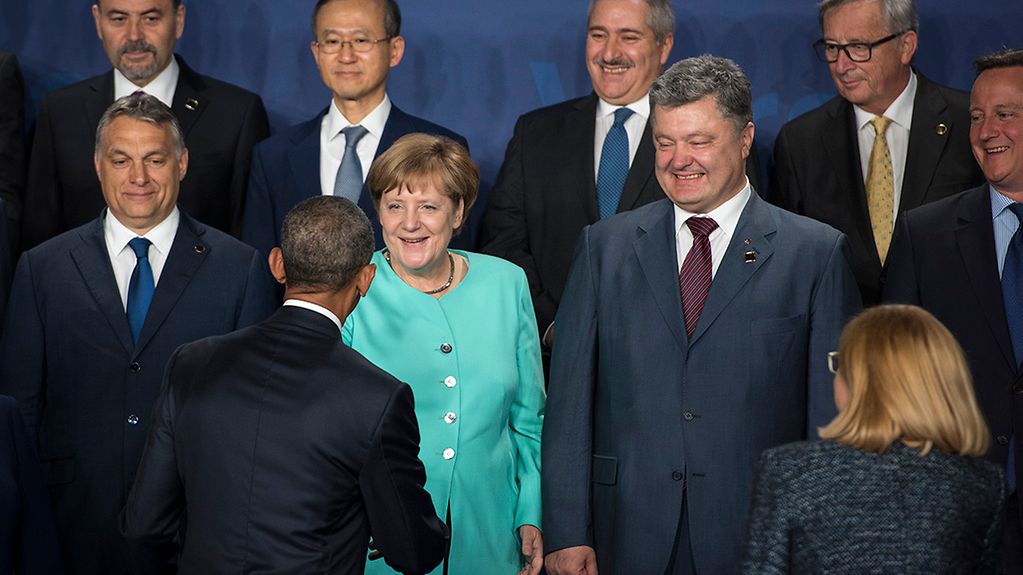 US-Präsident Barack Obama begrüßt Bundeskanzlerin Angela Merkel beim Familienfoto des Nato-Gipfels.