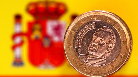 Eine Ein-Euro-Münze mit dem Bild von Juan Carlos vor der spanischen Flagge.