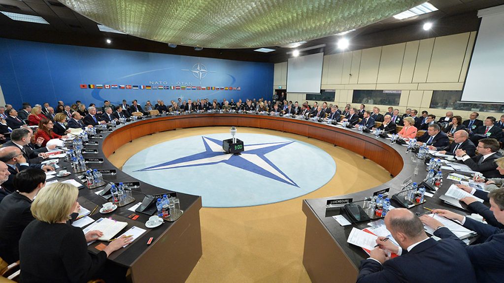 Les délégués assis à une grande table ronde en salle de réunion