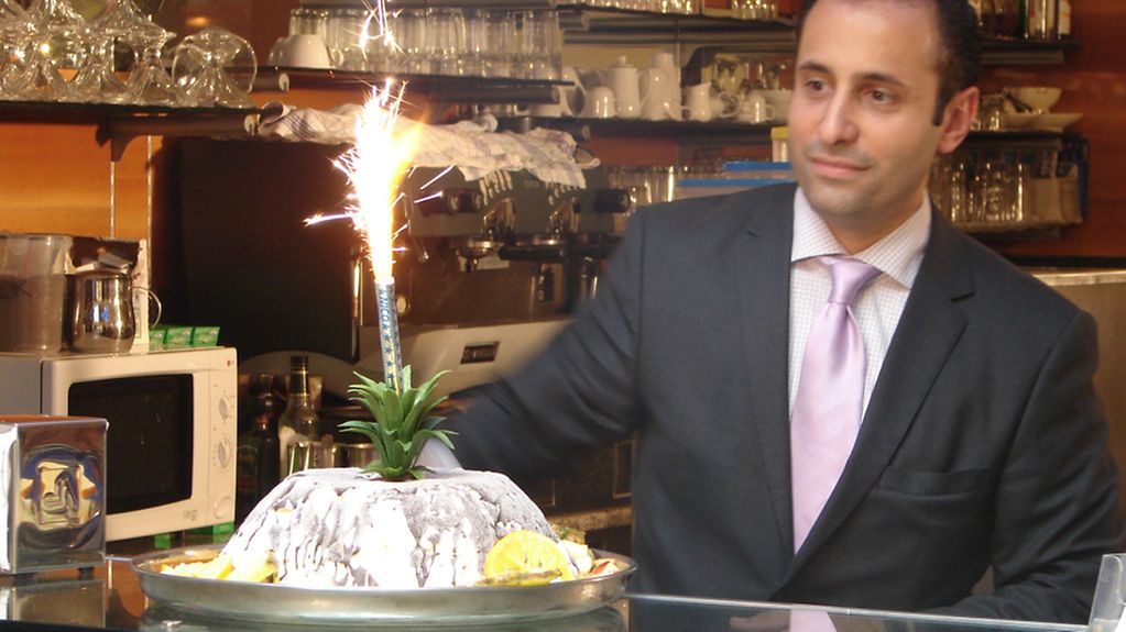 Marcello Camerin, Inhaber des Eis-Café Camerin aus Stadtallendorf bei Marburg, serviert am Tresen seines Eis-Cafes eine Eisbombe