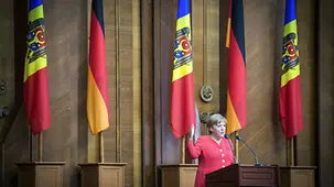Merkel bei der Rede vor Fahnen.