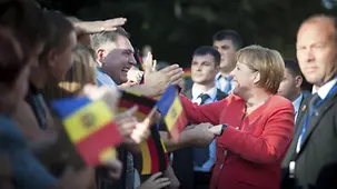 Merkel schüttelt Zuschauern mit Fähnchen die Hände.