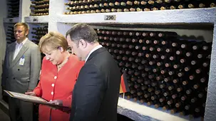 Merkel und Ministerpräsident Filat vor einem Weinregal.