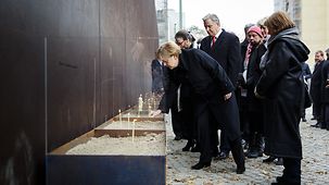 Bundeskanzlerin Angela Merkel steckt eine Rose zwischen die Steine der ehemaligen Grenzanlage an der Bernauer Straße.