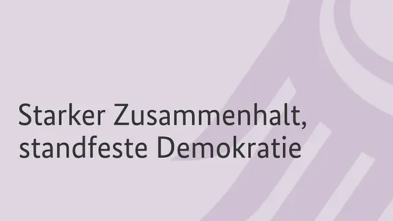 Grafik mit stilisierte Bundesadlerschwinge mit der Aufschrift "Starker Zusammenhalt, standfeste Demokratie".