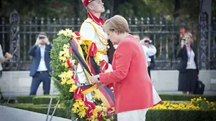 Angela Merkel straigtens the ribbons on the wreath.
