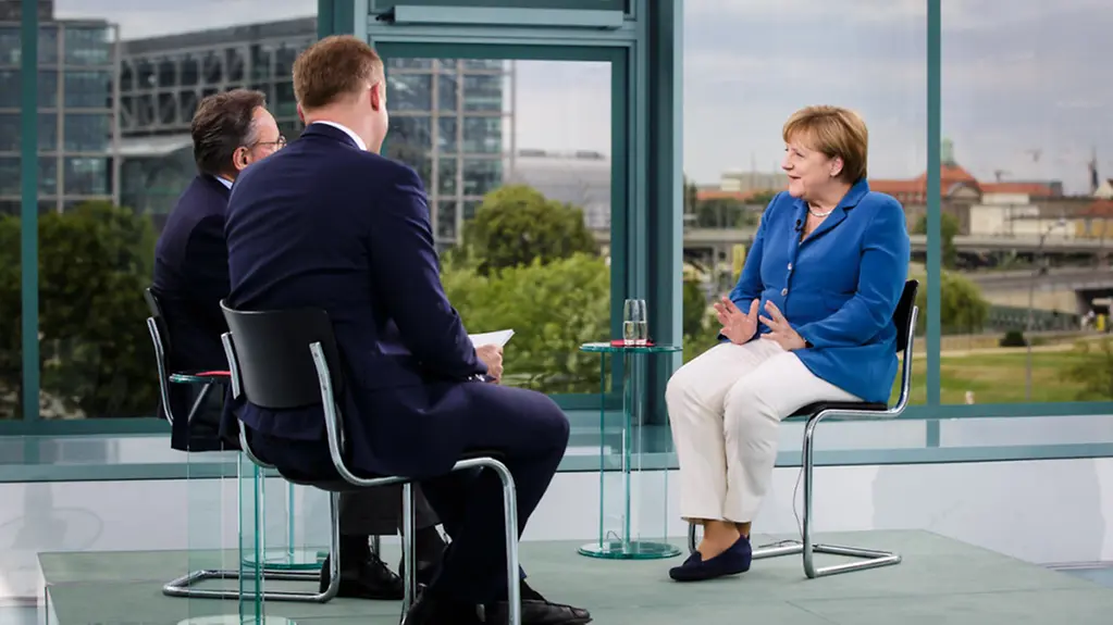 Merkel im Gespräch mit zwei Journalisten