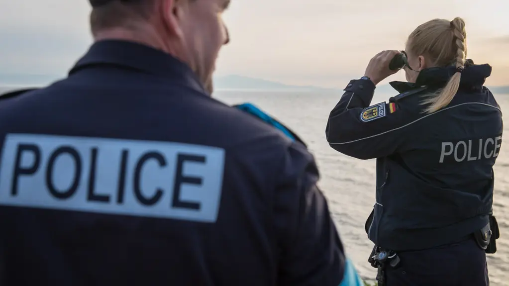 Polzeibeamte mit Ferngläsern halten nach Migranten an der Küste Griechenlands Ausschau.