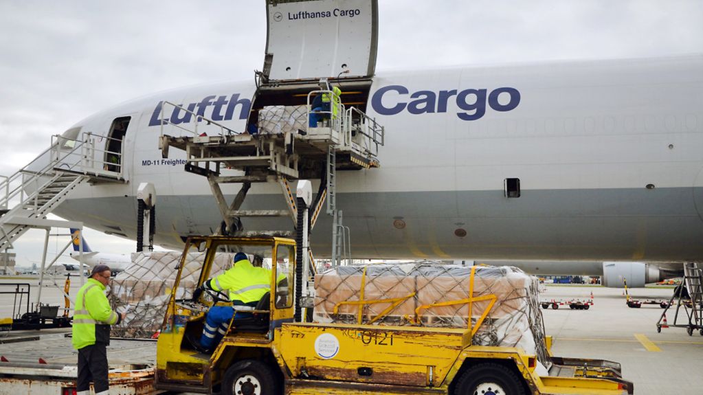 Eine MD-11 der Lufthansa Cargo wird auf dem Rhein-Main-Flughafen in Frankfurt über einen Hubwagen mit Fracht-Containern beladen.