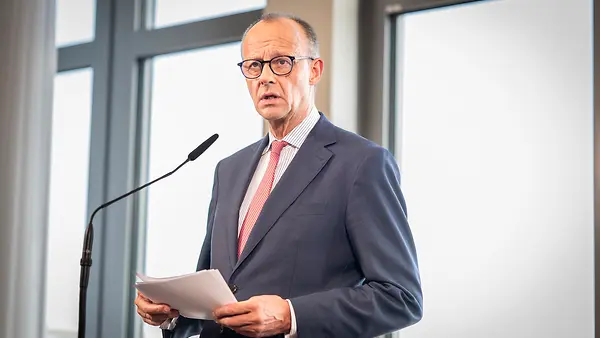 Bundeskanzler Friedrich Merz mit Papier in der Hand am Flughafen in Berlin während eines Statements.