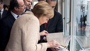 Bundeskanzlerin Angela Merkel betrachtet das Gastgeschenk des französischen Präsidenten François Hollande.