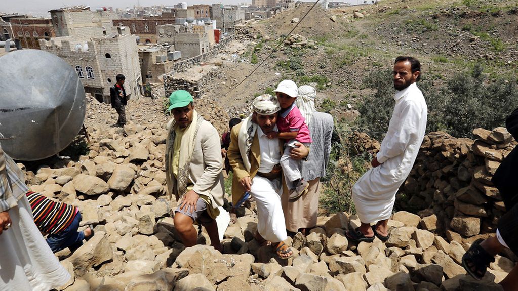 À Sanaa, la capitale du Yémen, des habitants marchent sur les décombres de leur maison détruite lors de raids aériens