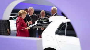 Bundeskanzlerin Angela Merkel blickt in den Kofferraum eines Autos.
