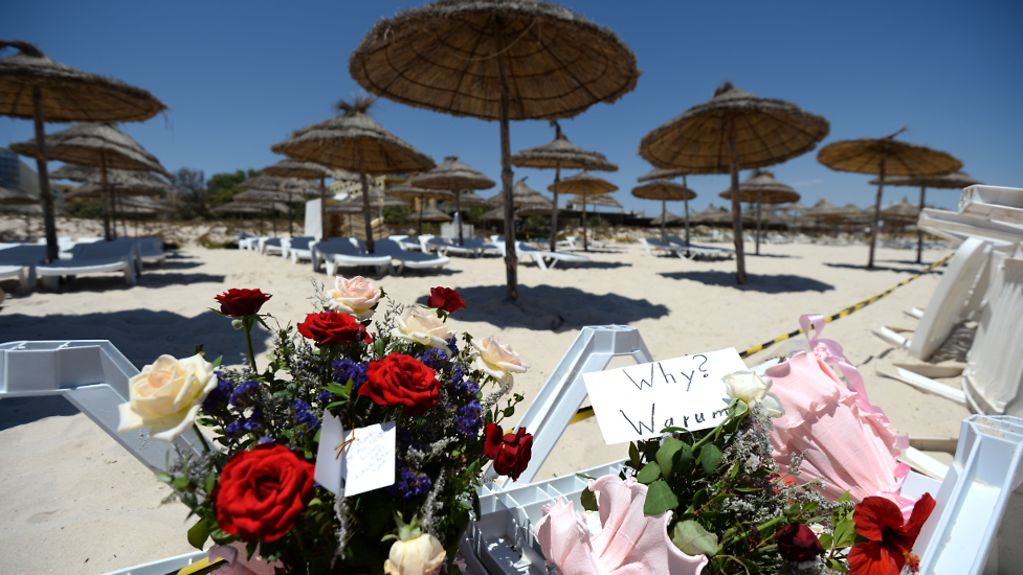 Flowers and a sign reading "Why?- Warum?" at the beach where the terrorist attack took place in Tunisia