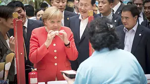 Bundeskanzlerin Merkel probiert Lebensmittel.