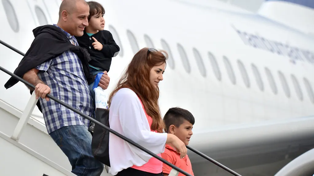 Syrische Familie geht die Gangway eines Flugzeugs hinunter.