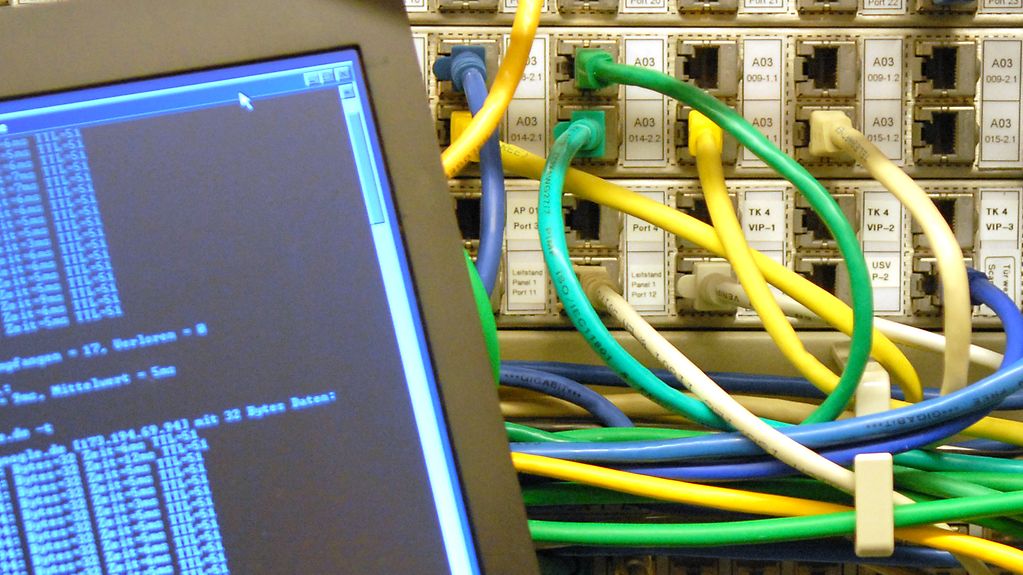 Ein Laptop steht vor Netzwerkkabeln in einem Serverschrank.