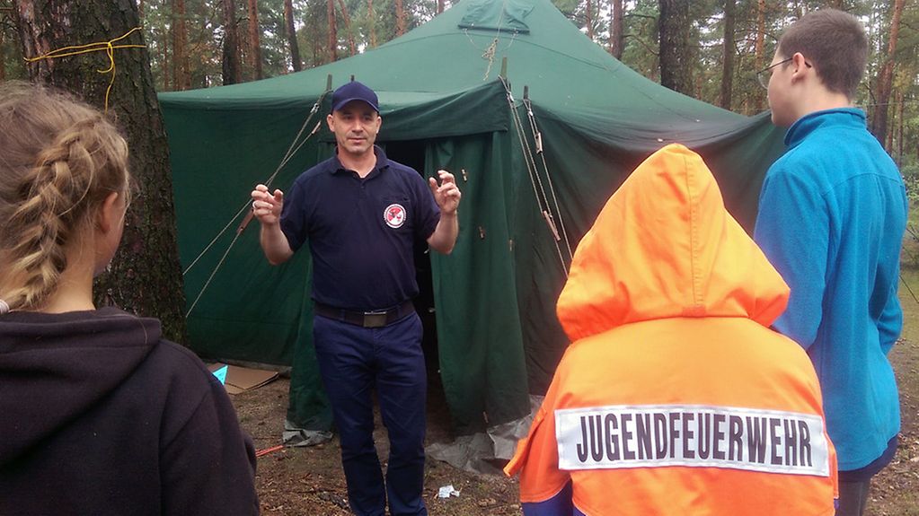 Ingo Bröcker spricht mit Jugendlichen in einem Jugend-Camp der Landesjugendfeuerwehr Brandenburg.