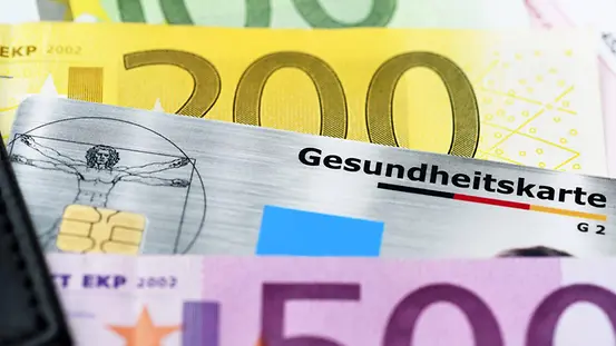 Eine Krankenversichertenkarte inmitten von Gelscheinen.