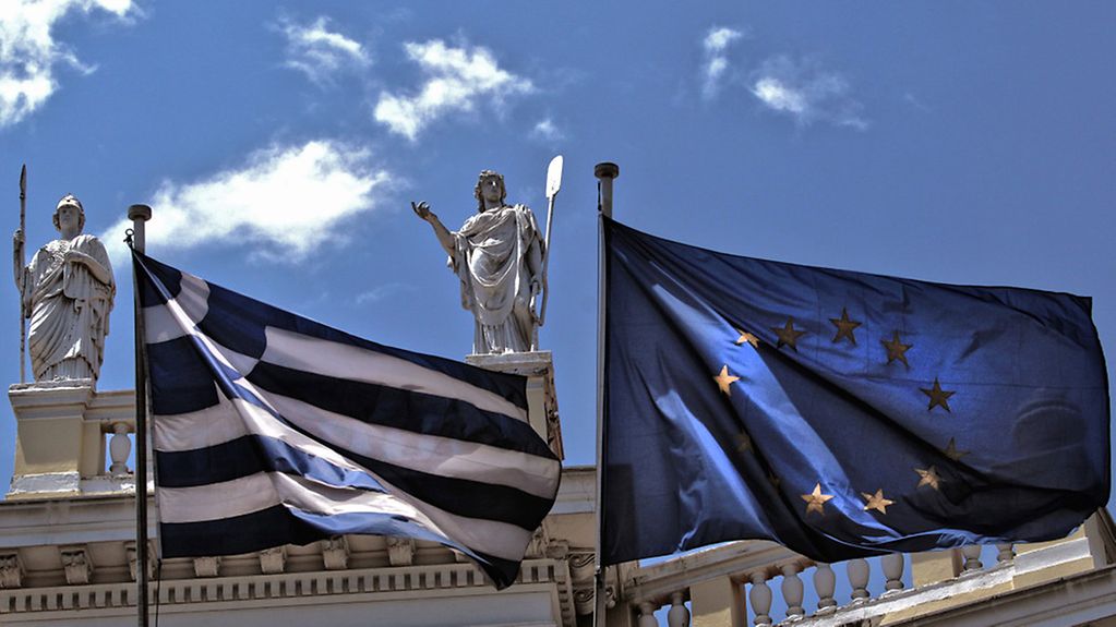 Photo prise le 20 juin 2015 et mise à disposition le 21 juin : drapeau grec (à gauche) et drapeau européen (à droite) flottant sous les statues d'anciens dieux grecs érigées sur le toit d'un bâtiment situé en plein cœur d'Athènes