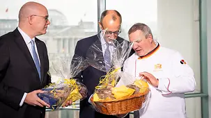 Das Foto zeigt Bundeskanzler Friedrich Merz, der einen Brotkorb überreicht bekommt.
