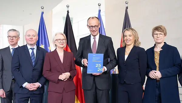 Auf dem Foto zu sehen sind Bundeskanzler Friedrich Merz und der Sachverständigenrat Wirtschaft bei der Übergabe des Jahresgutachtens 2025/26. 
