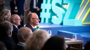 Das Foto zeigt Bundeskanzler Friedrich Merz im Publikum beim SZ-Wirtschaftsgipfel.