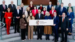 Das Foto zeigt Bundeskanzler Friedrich Merz und seine KabinettskollegInnen bei einem Fototermin zur Olympia-Bewerbung.