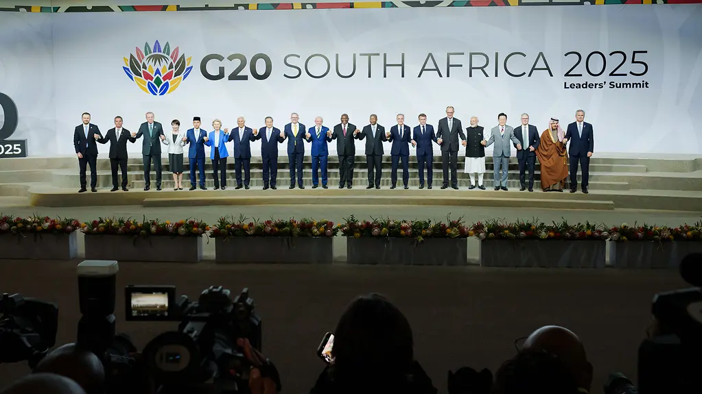 The photo shows heads of state and government holding hands on a stage at the G20 meeting in South Africa.