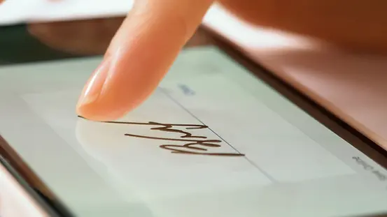 Nahaufnahme einer digitalen Unterschrift auf dem Smartphone-Bildschirm mit einer Frauenhand.