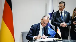 Bundeskanzler Merz unterschreibt am Tisch, daneben steht der Präsident des Staates Israel, Isaac Herzog