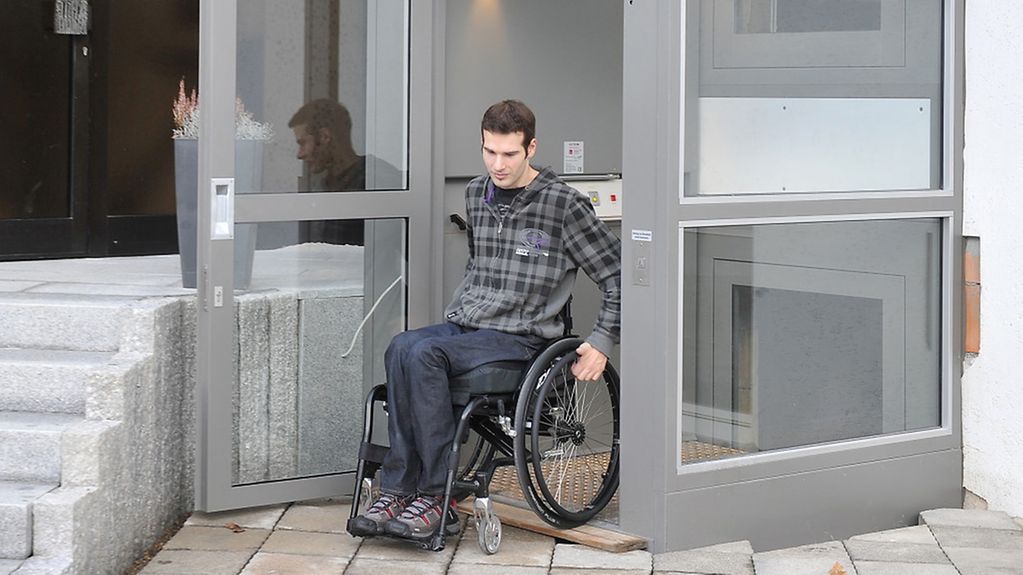 Ein Rollstuhl-Fahrer kommt aus einem Fahrstuhl.